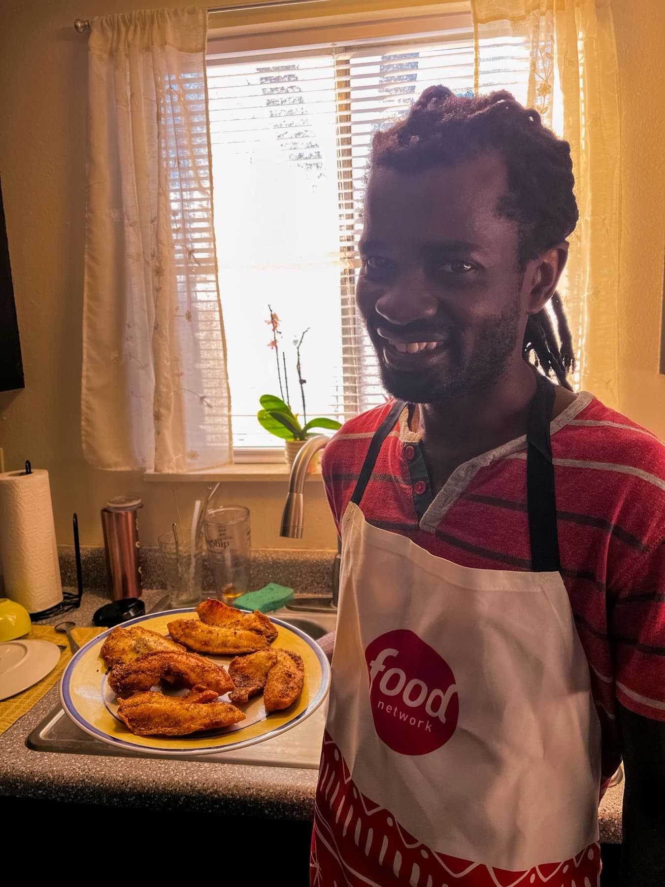 A creator-chef holding a plate of fried fish